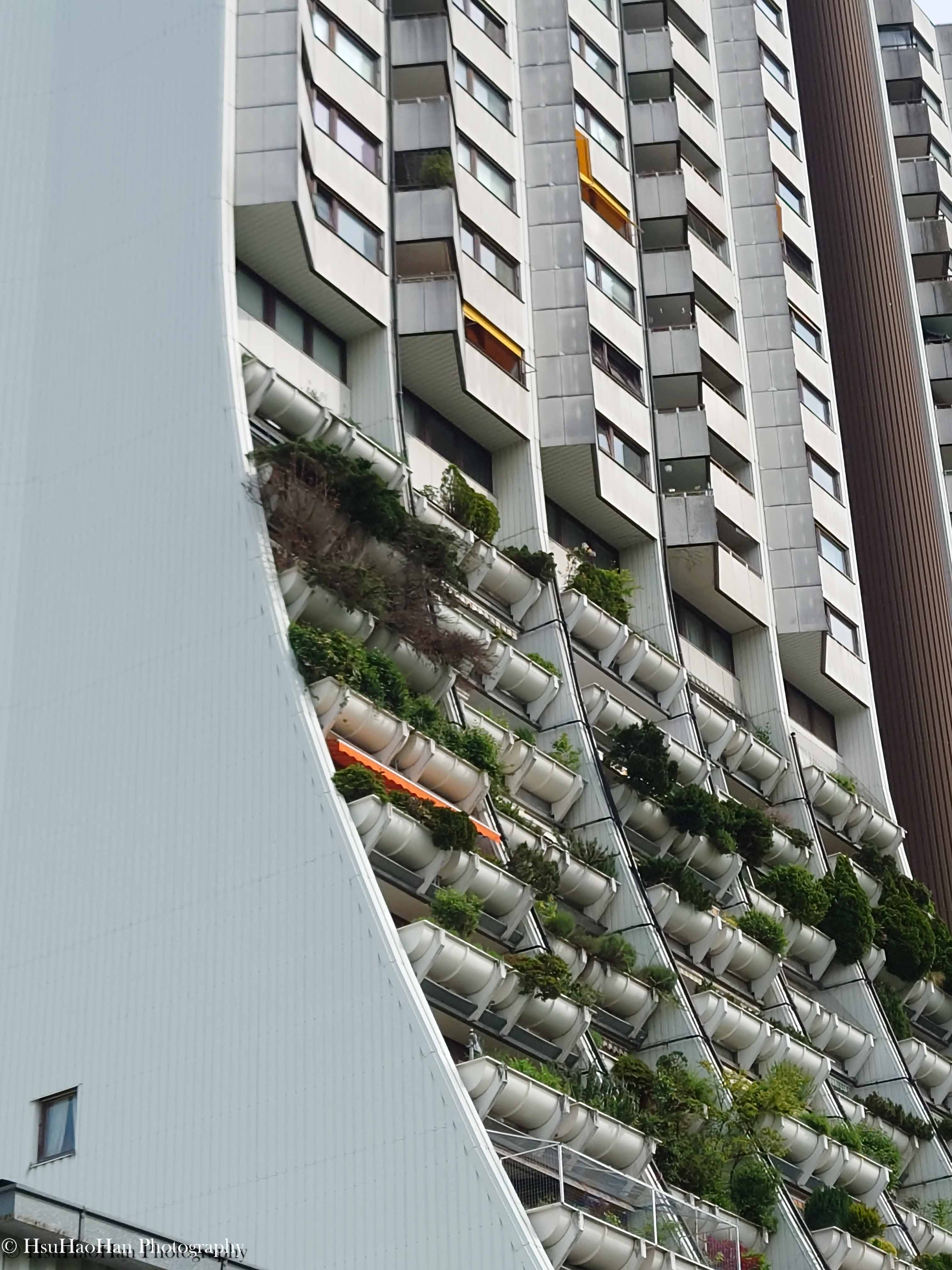 維也納 Wohnpark Alterlaa 建築的局部，巨大的白色弧形牆面與種滿植物的階梯式露台形成有趣的交會。