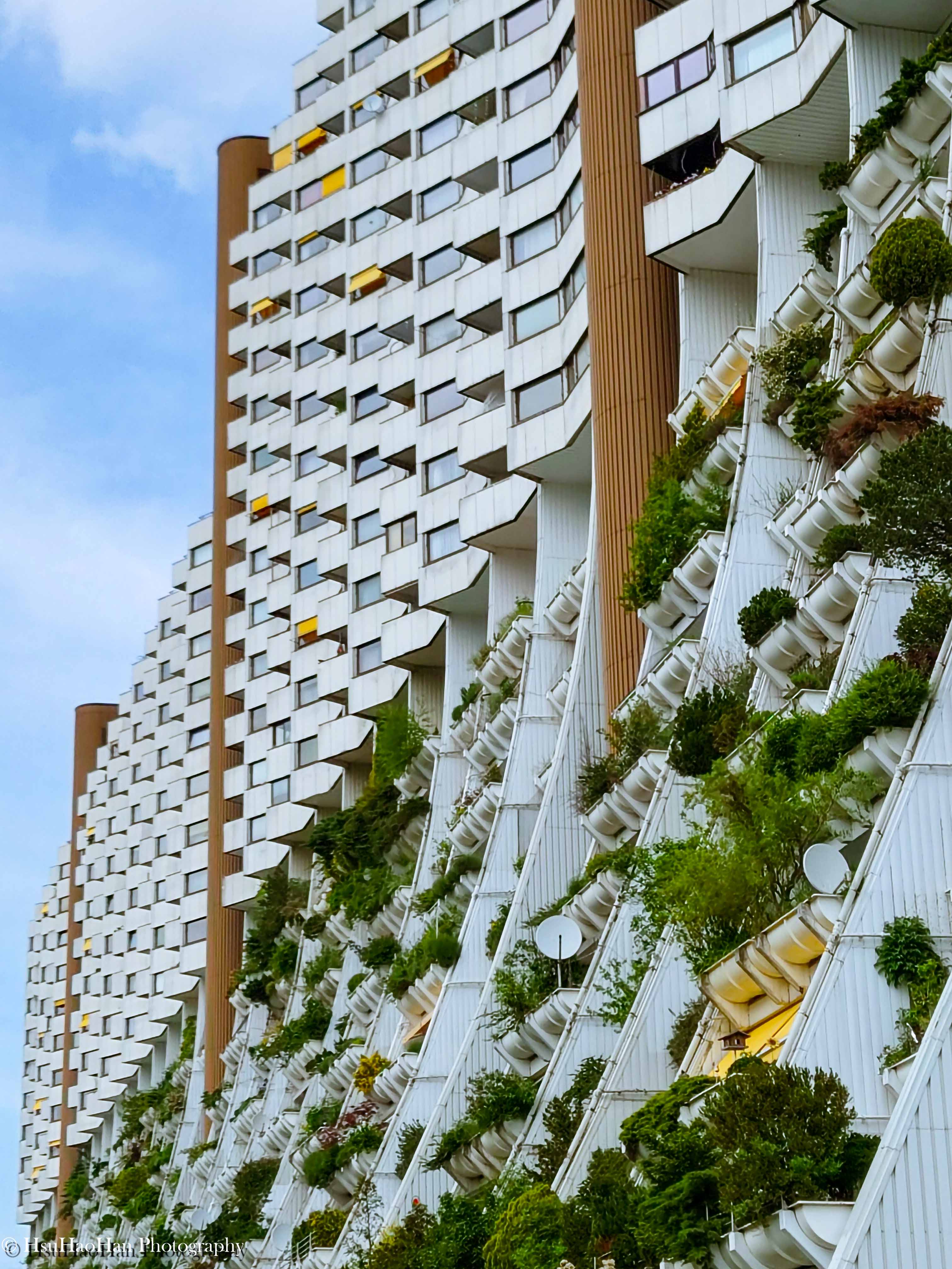 維也納 Wohnpark Alterlaa 住宅的階梯式立面，充滿韻律感的白色露台花槽與其上的綠色植物，和後方平整的建築立面形成對比。
