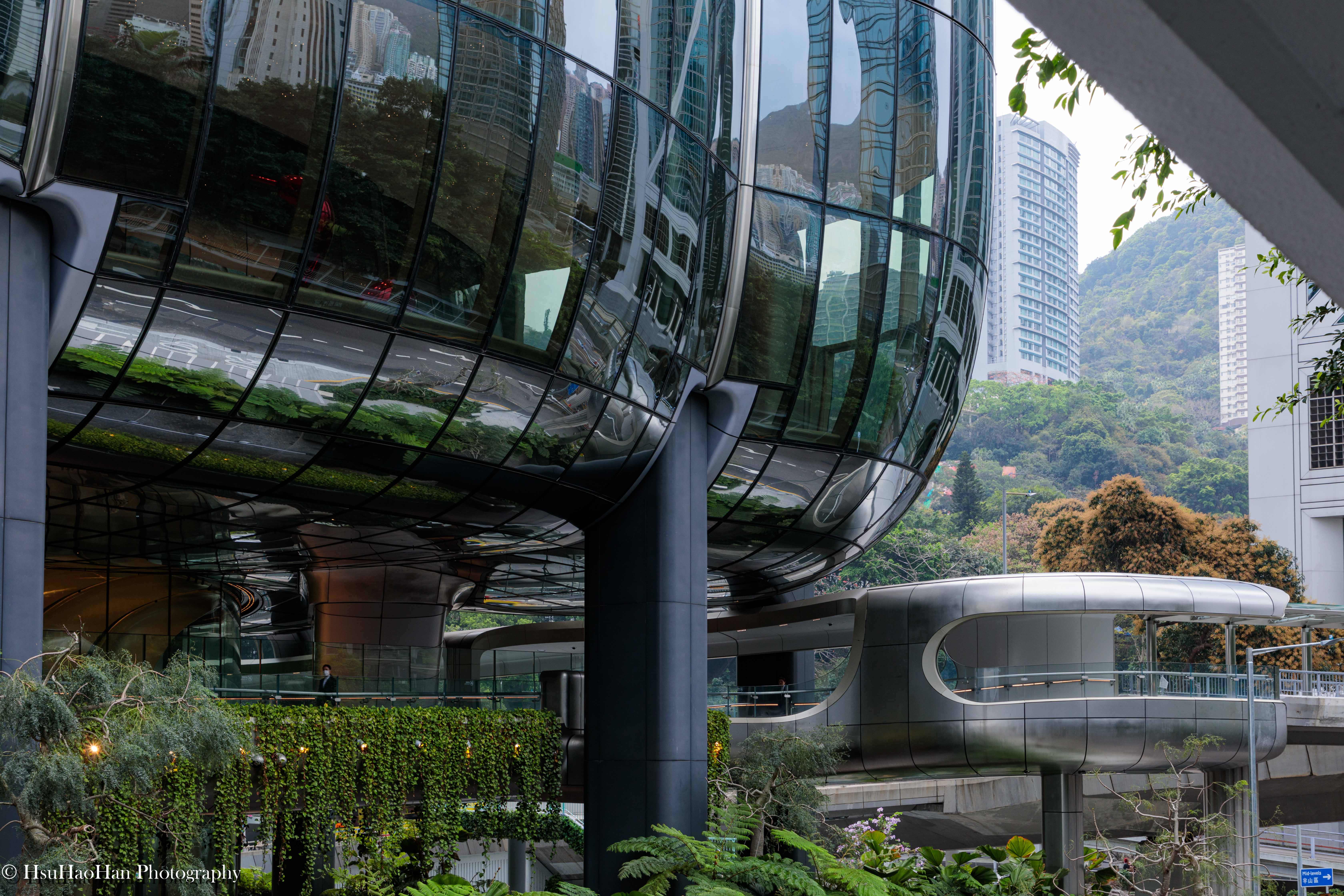 香港 The Henderson 大樓與其周圍的行人天橋系統，展現了建築有 機的曲線如何與城市的基礎設施無縫地連結。