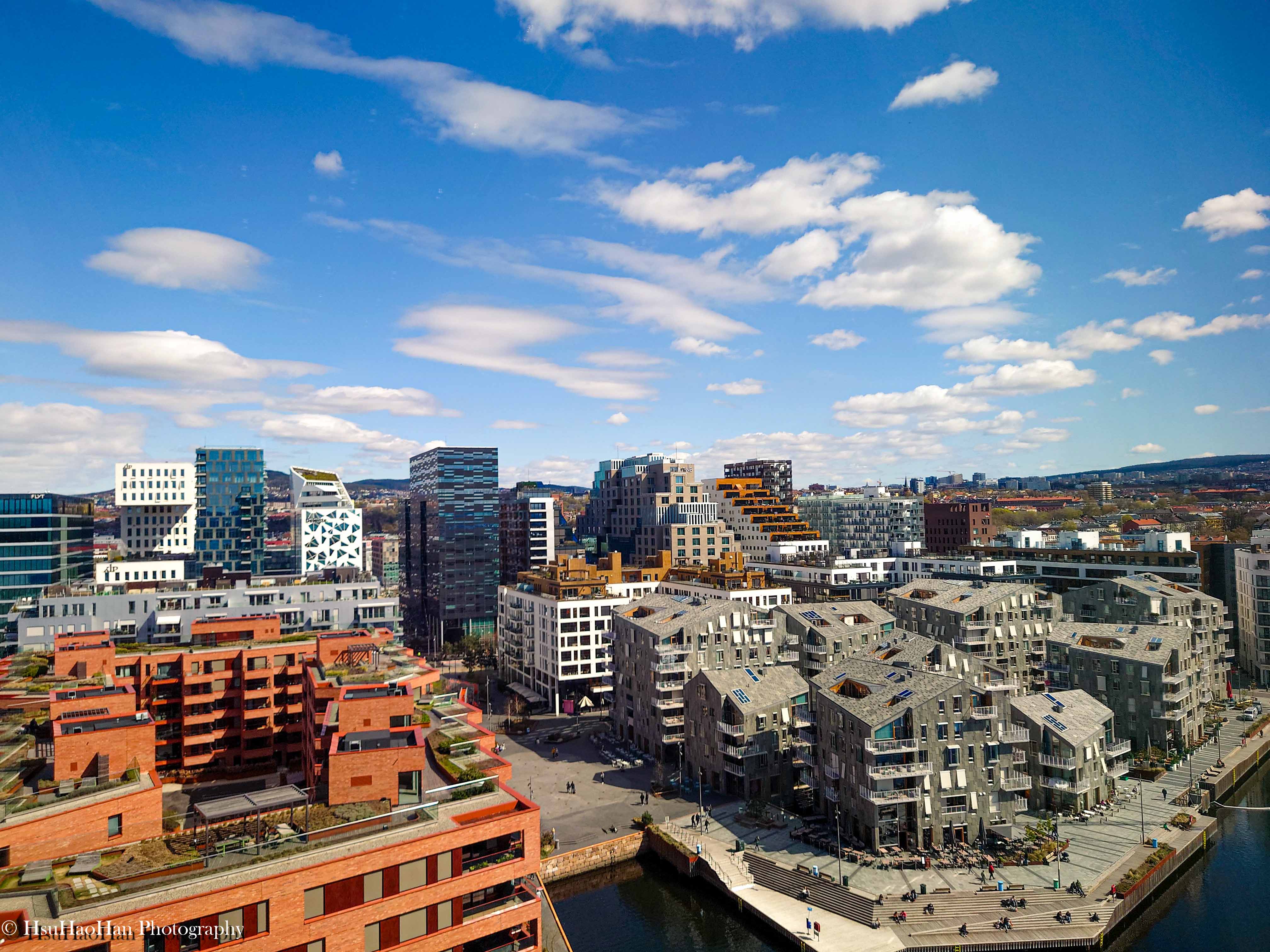 從高處俯瞰挪威奧斯陸的港灣區，前景是紅磚的Sørenga住宅區，背景是高聳、造型各異的「條碼計畫」摩天樓群。