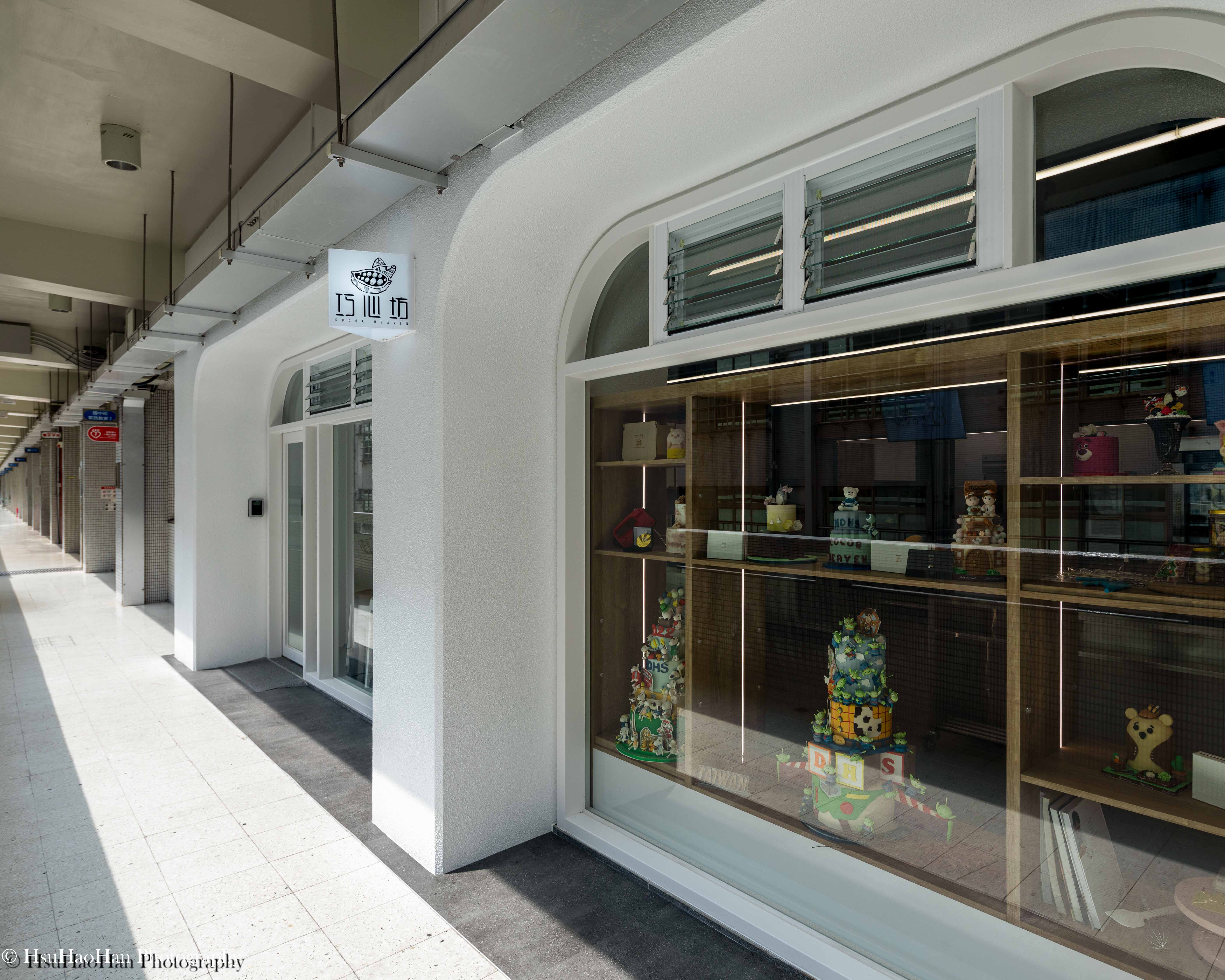 Exterior corridor storefront of Cocoa Heaven featuring arched windows and cake display - 明道中學巧心坊教室外觀白色拱窗設計與學生蛋糕作品櫥窗展示 - Photography by Hsu Hao Han