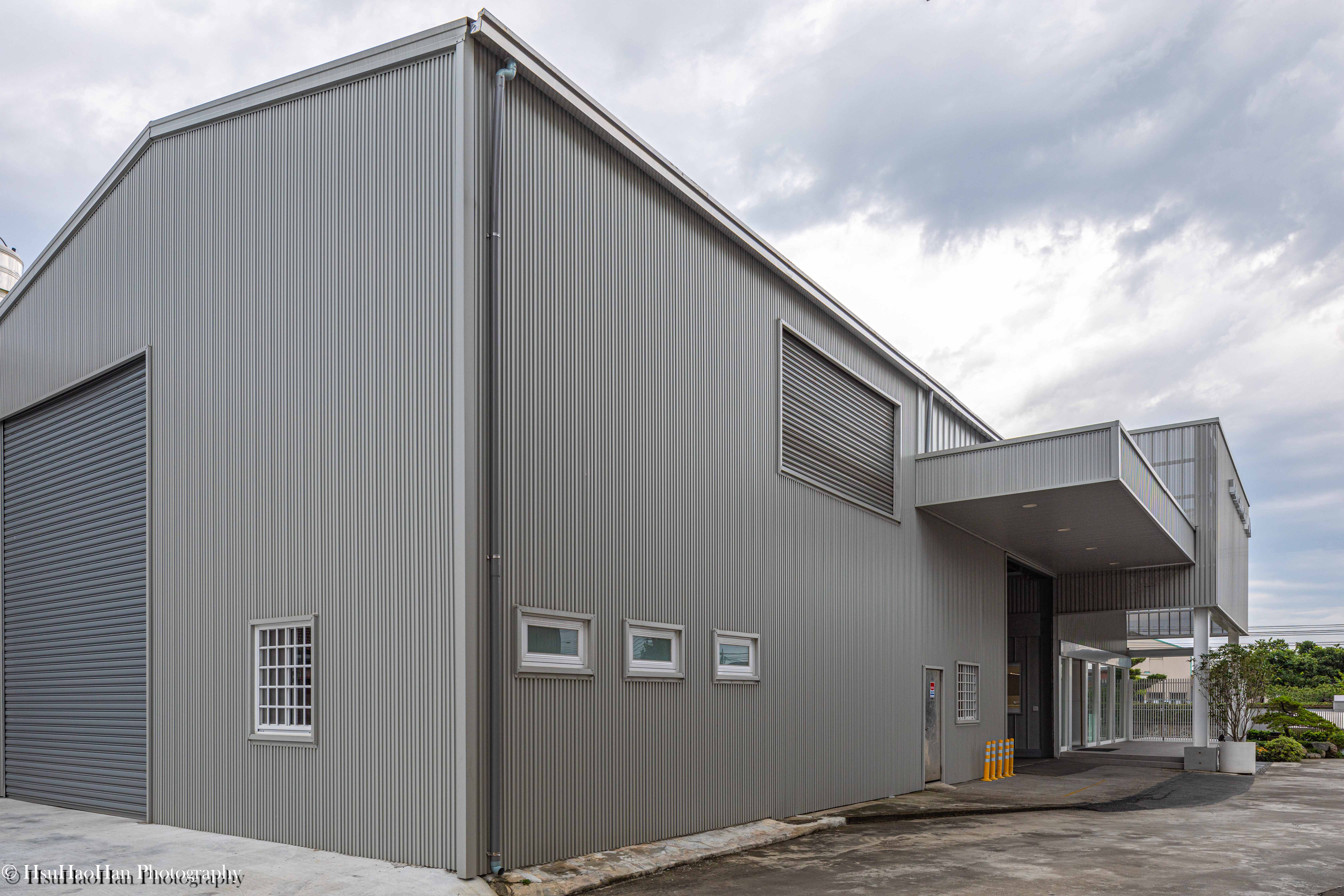 Large scale industrial warehouse exterior with grey vertical corrugated metal sheets - 誼冠鋼品大型鋼構廠房外觀與灰色垂直浪板建材特寫 - Photography by Hsu Hao Han