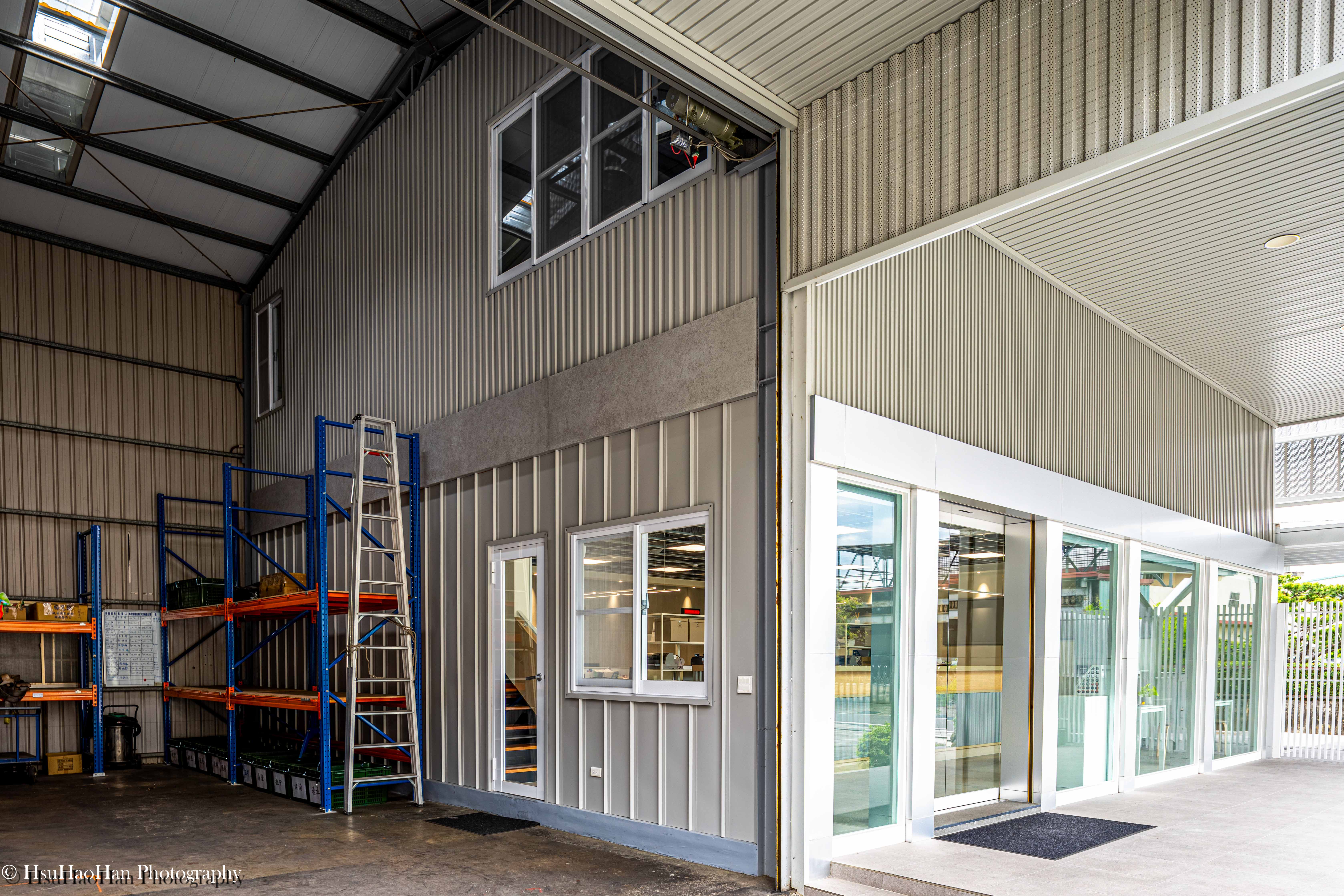 Interior view of high-ceiling steel warehouse connecting to office space with blue racking - 誼冠鋼品挑高鋼構廠房內部與辦公室連接空間及貨架收納 - Photography by Hsu Hao Han