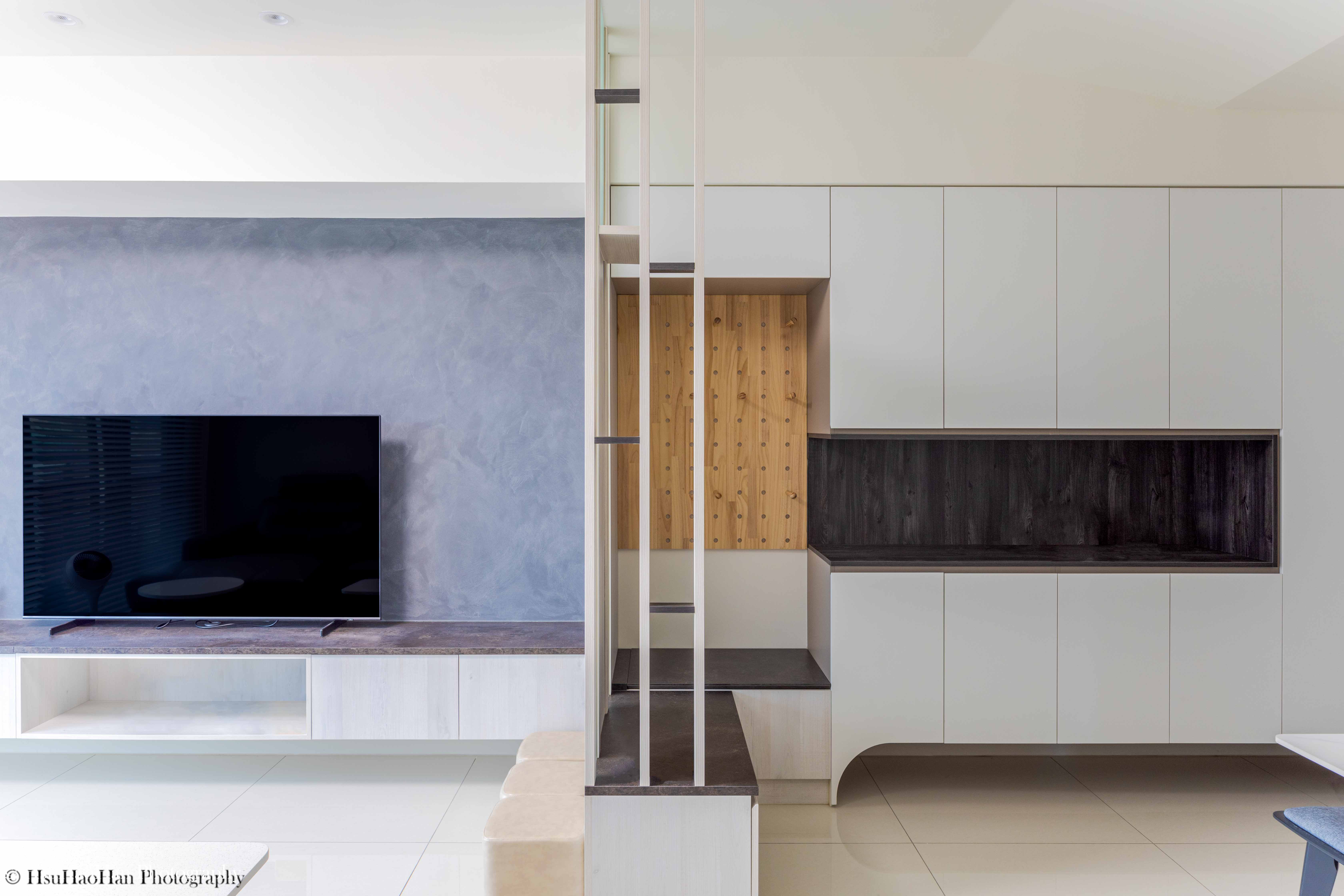 台中「黎民觀邸」的客廳電視牆，採用灰色特殊漆，下方是淺木色電視櫃，一旁的玄關隔屏則結合了深色與淺木色。