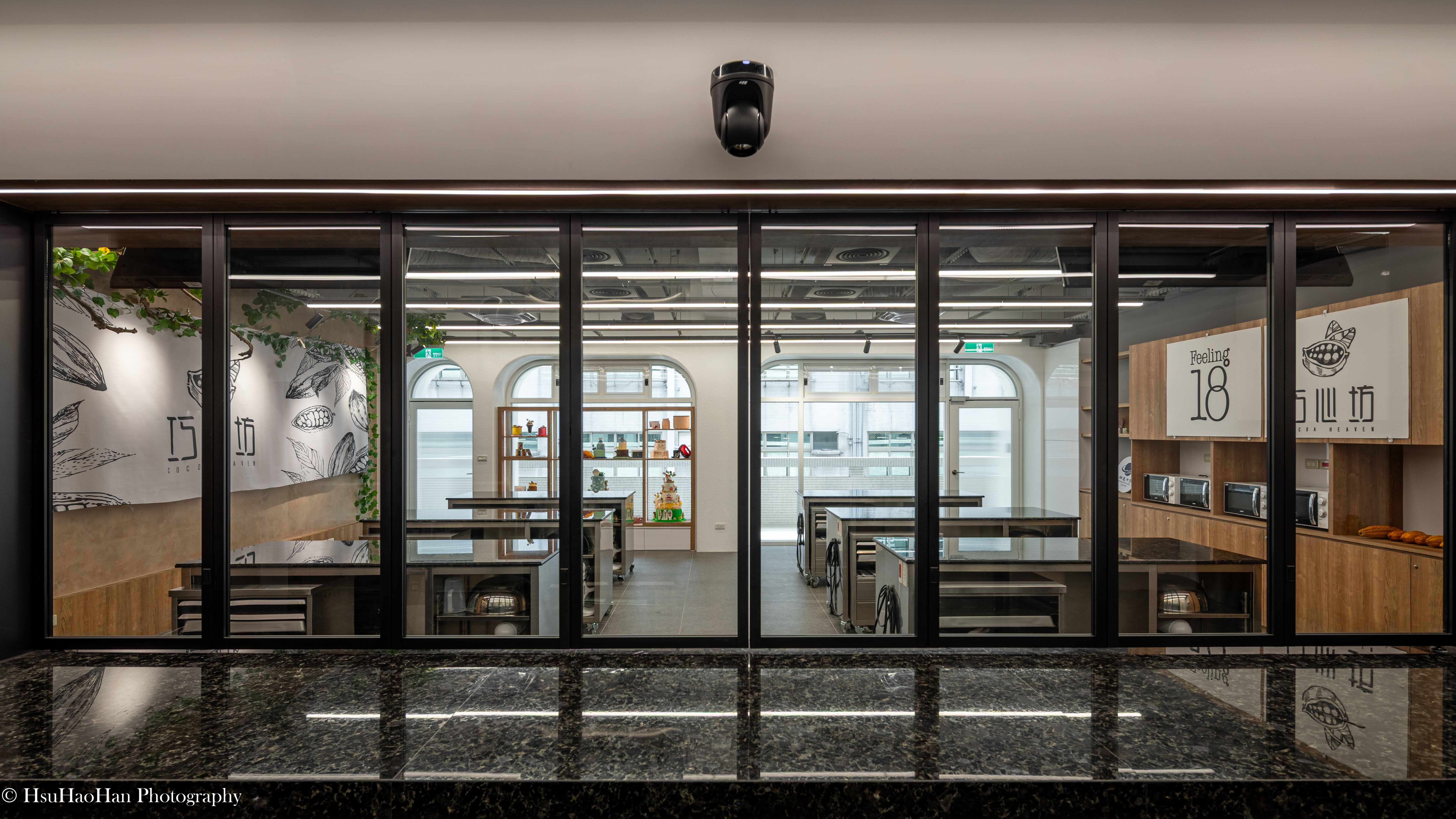 View through glass partition doors into the chocolate making classroom featuring Feeling 18 branding - 透過玻璃折疊門觀看巧心坊教室內部空間與 Feeling 18 聯名意象 - Photography by Hsu Hao Han