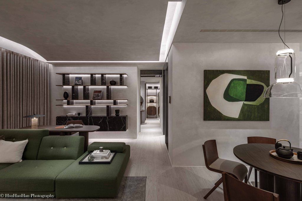 漢宇建設「漢宇雲衍」樣品屋的客廳與餐廳，由原建筑設計，空間以深綠色沙發、黑色大理石書架與質感塗料牆面，打造出沉穩的現代風格。