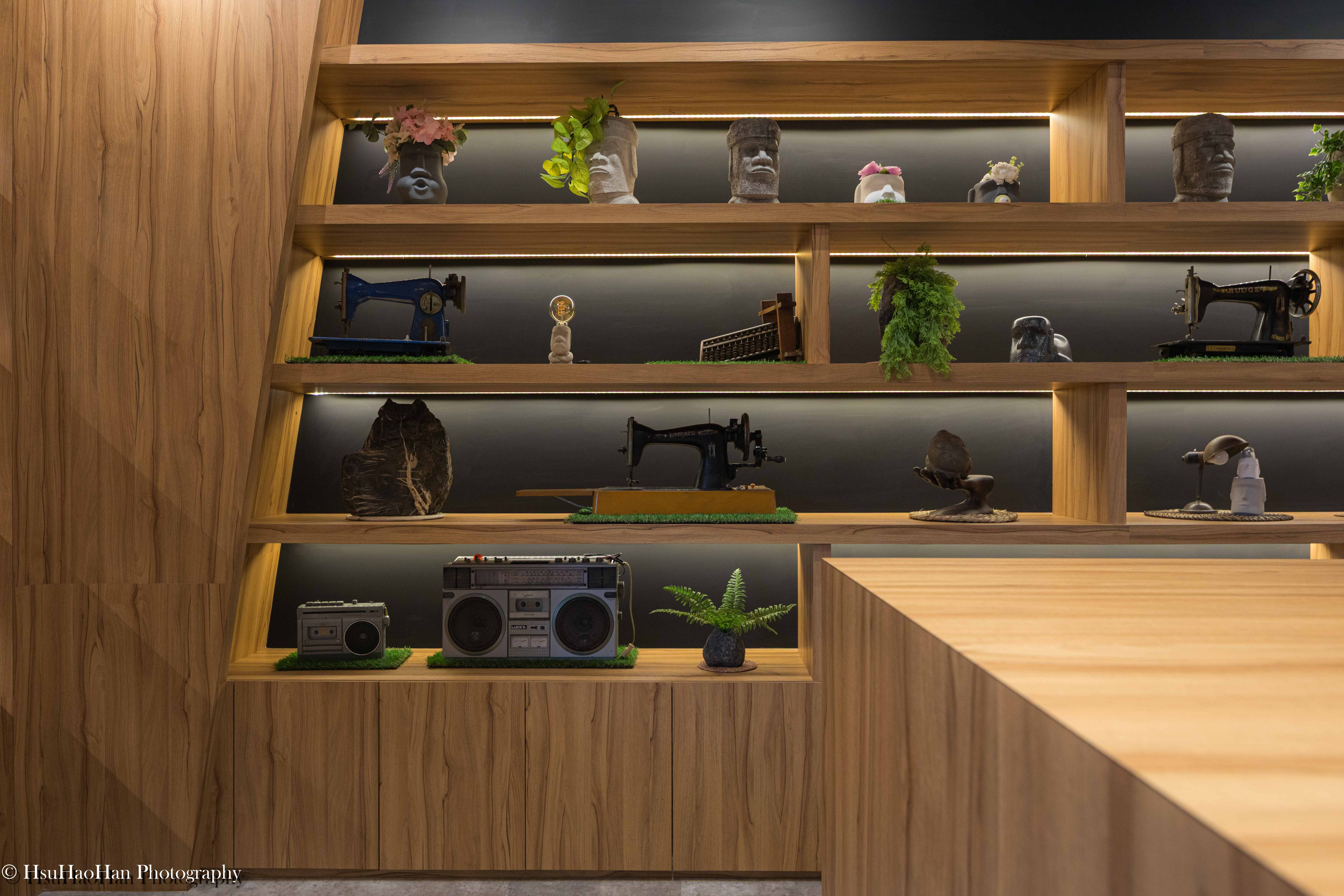 Wooden display shelves showcasing vintage sewing machines and Moai statues at the coffee story hall - 九二咖啡故事館內部木作層架展示復古縫紉機與摩艾石像 - Photography by Hsu Hao Han