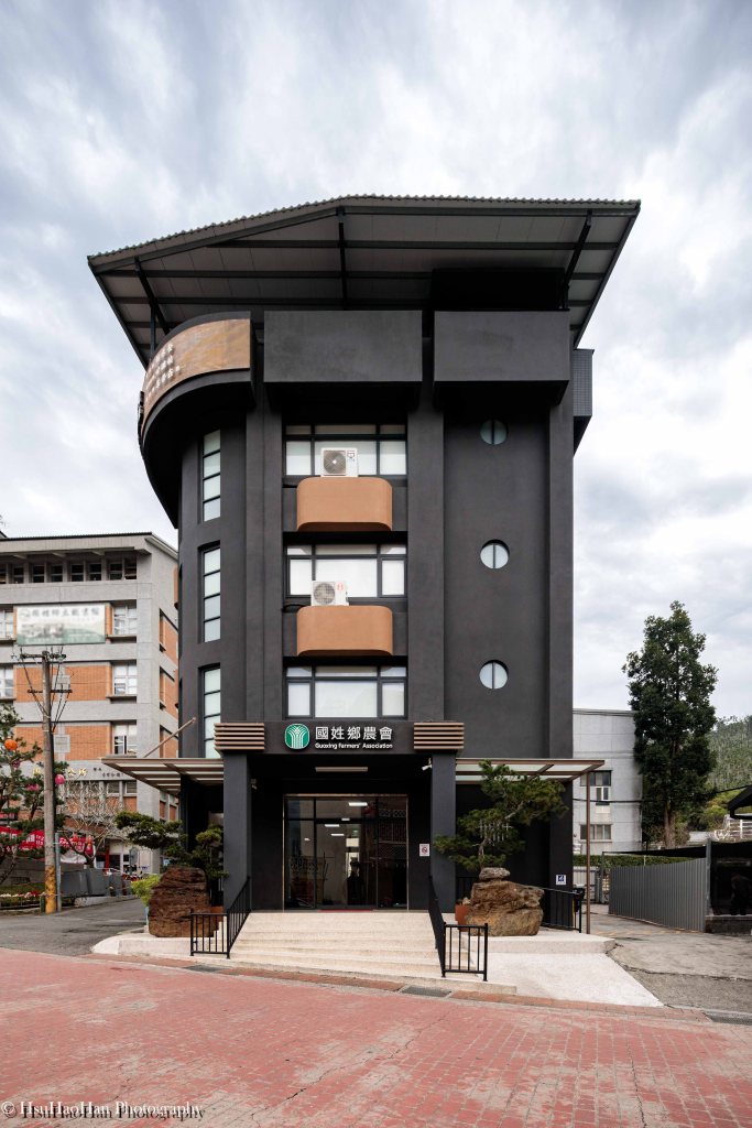Modern dark grey exterior architecture of Guoxing Township Farmers' Association headquarters featuring curved balconies and landscaping - 國姓鄉農會本部大樓現代建築外觀設計與黑色弧形陽台細節 - Photography by Hsu Hao Han