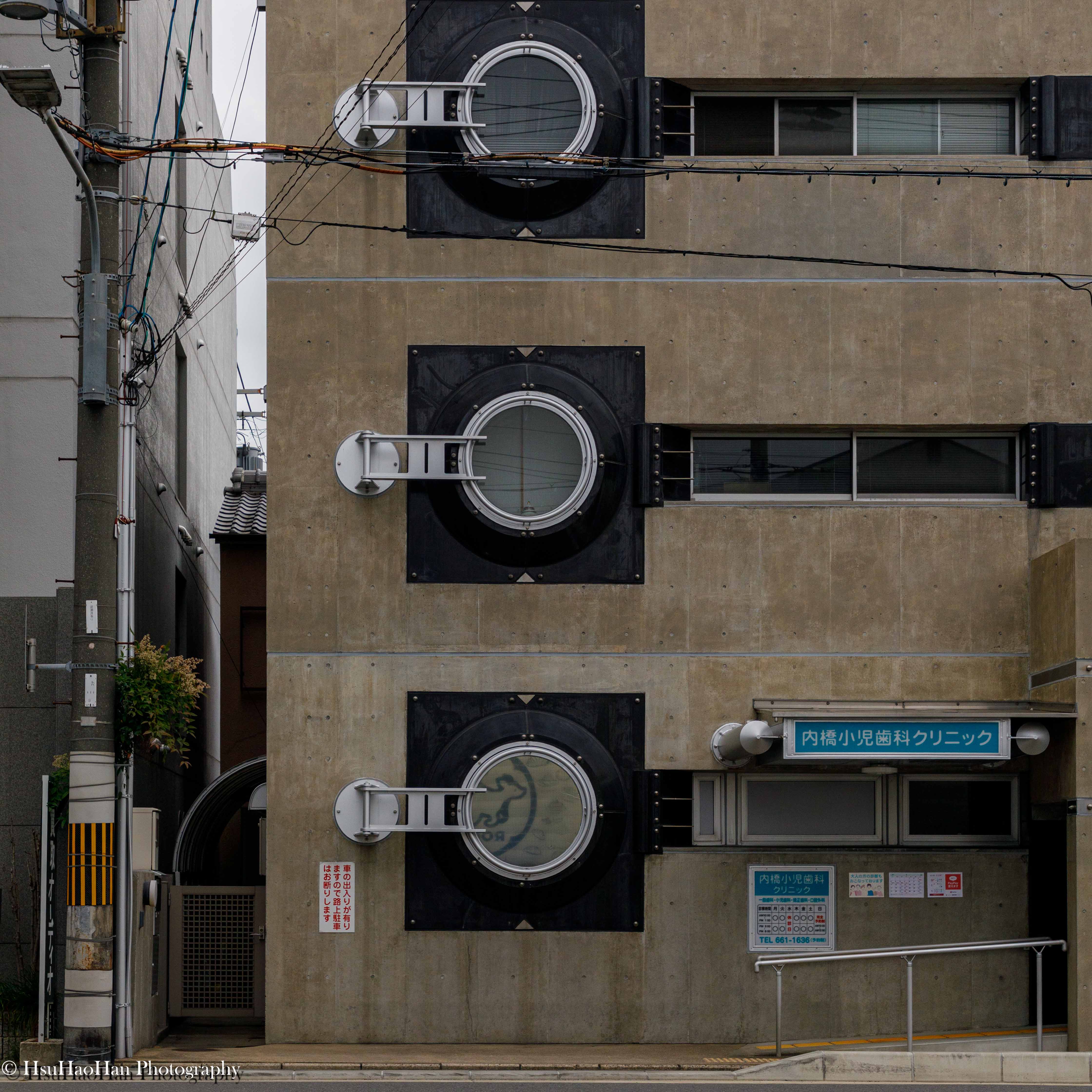 高松伸設計的京都建築 Pharaoh 立面細節，清水混凝土牆面上，裝飾著如同機械眼般的巨大圓形窗戶。
