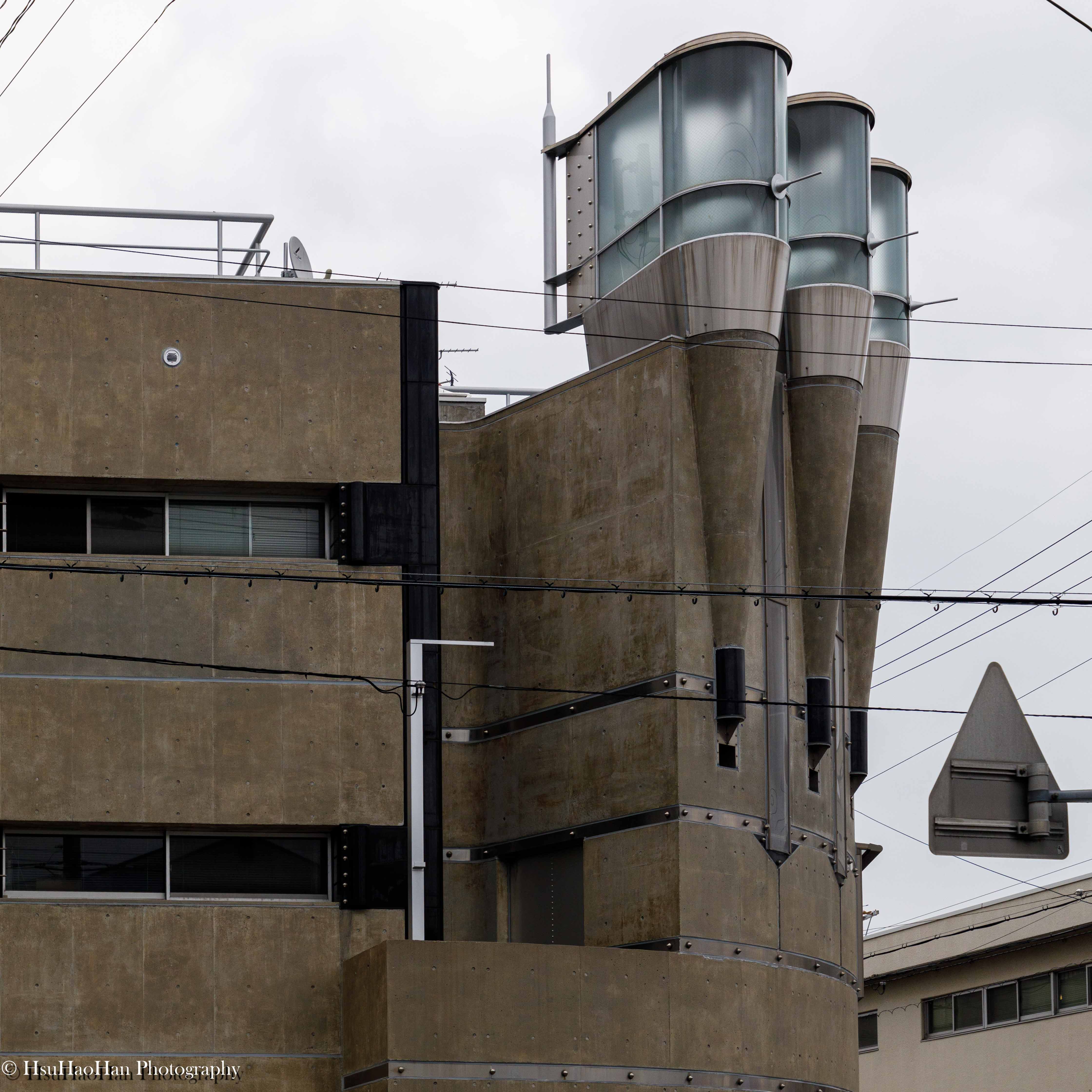 高松伸設計的京都建築 Pharaoh 屋頂細節，三個巨大的、帶有玻璃罩的金屬管狀結構，在陰天下呈現出強烈的機械美感。
